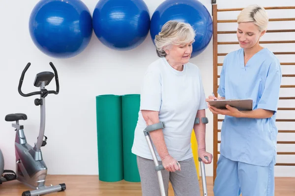 Therapist and senior woman looking at clipboard — Stock Photo, Image