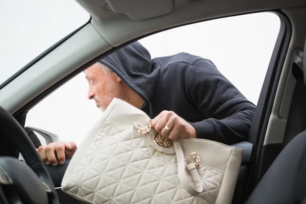 Thief breaking into car and stealing hand bag — Stock Photo, Image