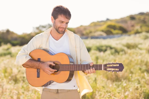 Lycklig man ler mot kameran spelar gitarr — Stockfoto