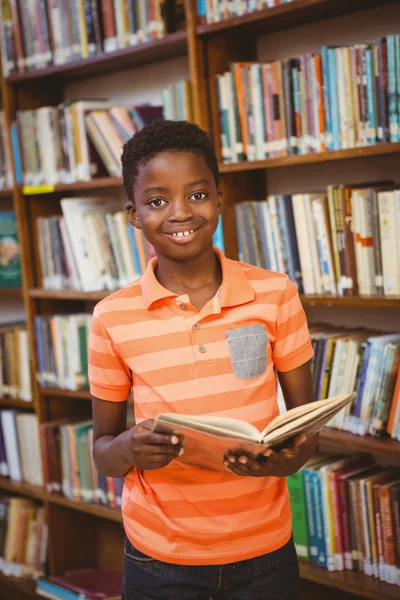 Cute boy reading book in library — Stock Photo, Image