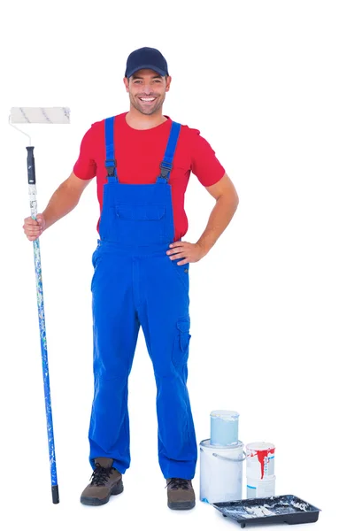 Handyman with paint roller standing by cans — Stock Photo, Image