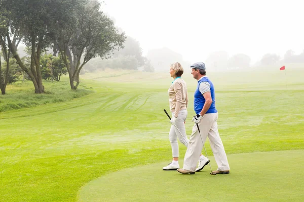 Golfing couple walking on putting green — Stock Photo, Image