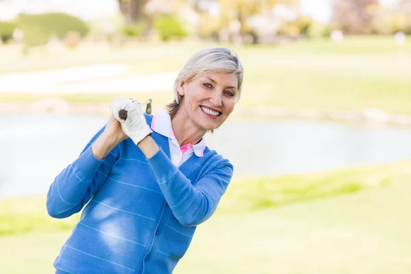 Golfista feminina de pé segurando seu clube sorrindo — Fotografia de Stock