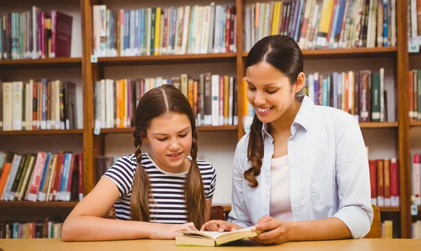 Lehrer und Mädchen lesen Buch in der Bibliothek — Stockfoto