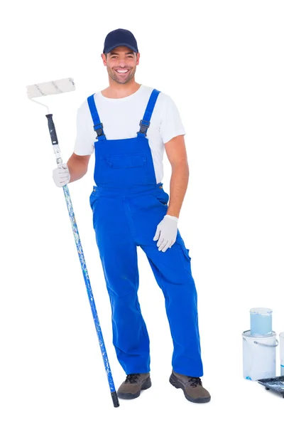Handyman with paint roller standing by cans — Stock Photo, Image
