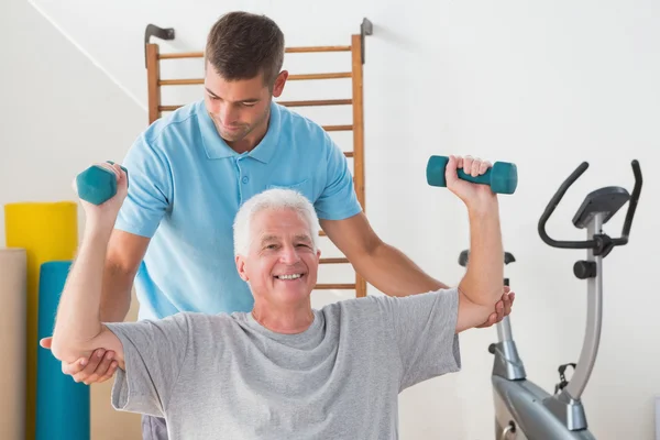 Senior man uit te werken met zijn trainer — Stockfoto