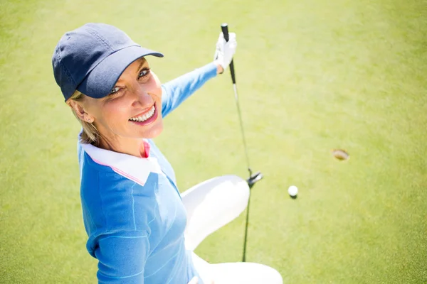 Femme souriante golfeuse agenouillée sur le putting green — Photo