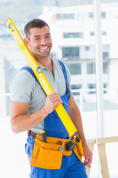 Repairman in overalls holding spirit level — Stock Photo, Image