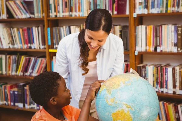 Leraar en boy kijken naar globe in bibliotheek — Stockfoto