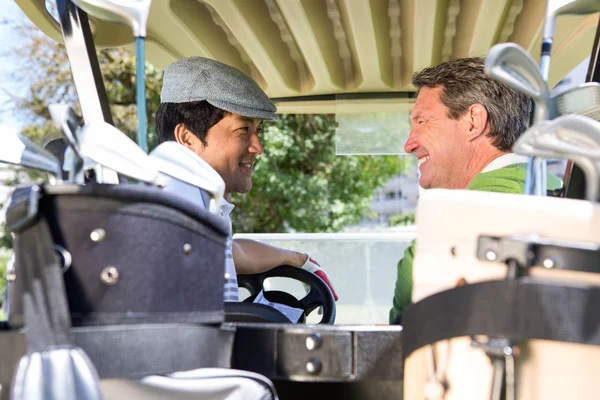 Golfing friends driving in their golf buggy — Stock Photo, Image