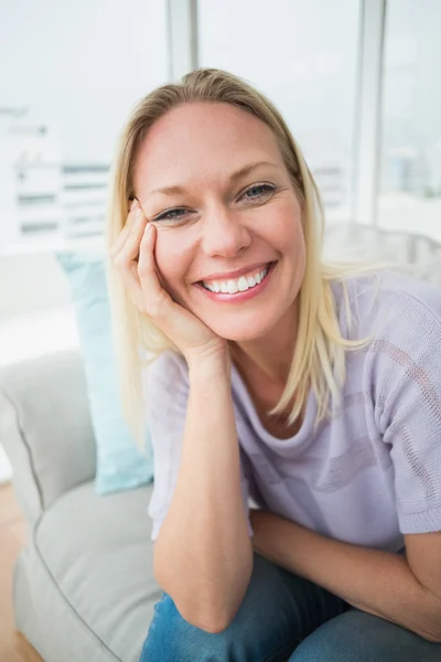 Mujer sonriente sentada en el sofá —  Fotos de Stock