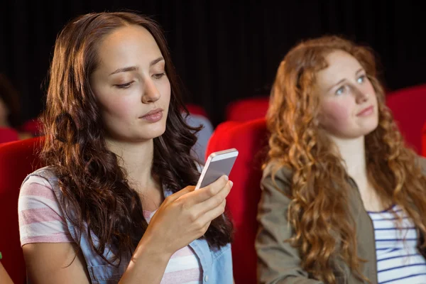 Woman text messaging on her mobile during movie — Stock Photo, Image