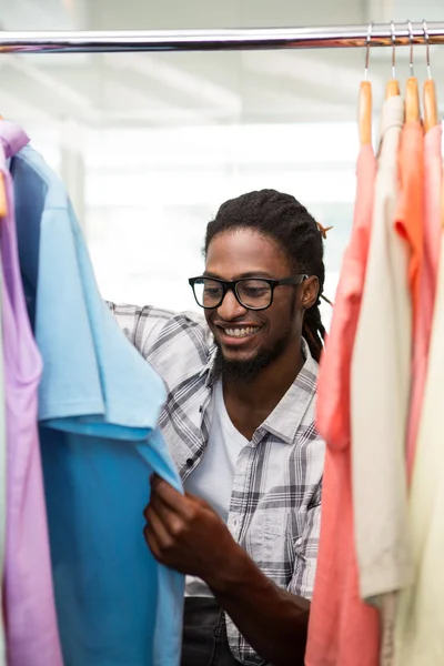 Männlicher Modeschöpfer schaut auf Kleiderständer — Stockfoto