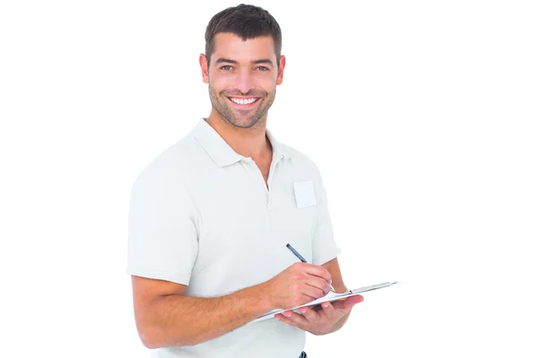 Smiling male handyman writing on clipboard — Stock Photo, Image