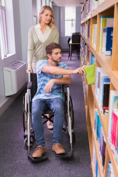 Studente sorridente disabile con compagno di classe in biblioteca — Foto Stock