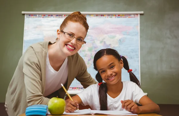 Leraar bijstaan meisje met huiswerk in klas — Stockfoto