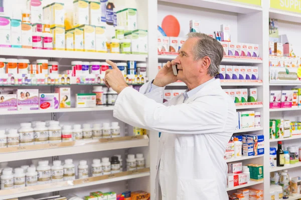 Pharmacien concentré au téléphone pointant le médicament — Photo