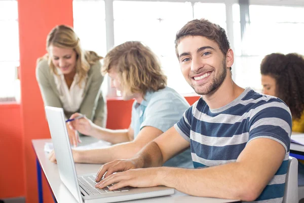 微笑的男学生在教室里使用笔记本电脑 — 图库照片