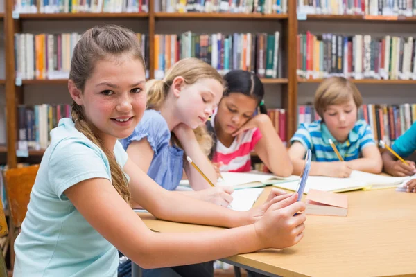 Cute pupil using tablet computer in library — Stock Photo, Image