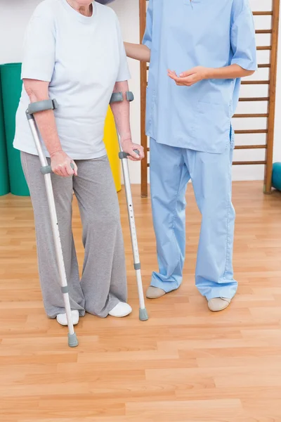 Therapeut helpen senior vrouw met scrubs — Stockfoto
