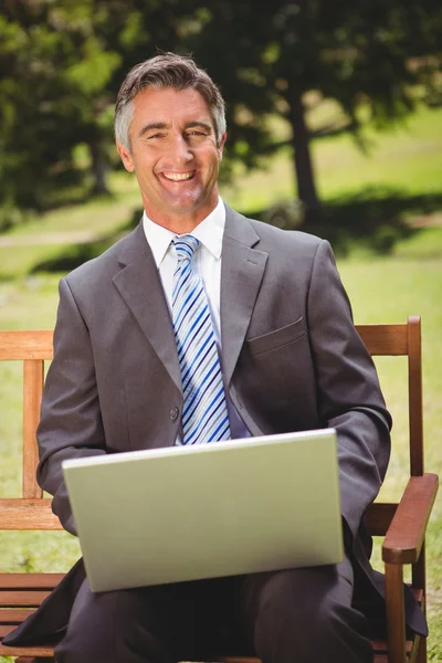 Uomo d'affari che utilizza il computer portatile nel parco — Foto Stock