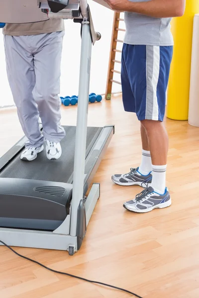 Hombre mayor en cinta de correr con entrenador —  Fotos de Stock