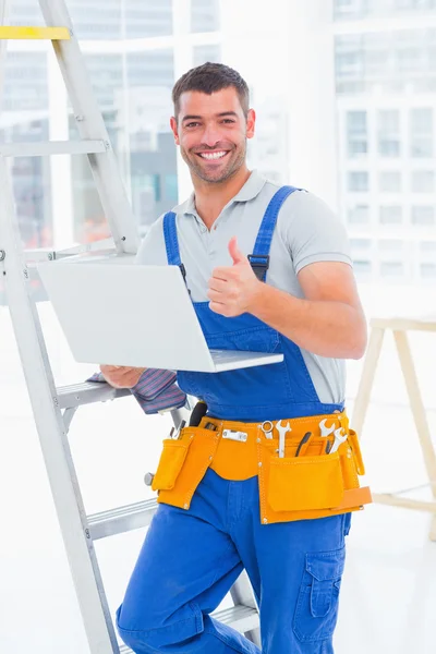 Smiling handyman with laptop — Stock Photo, Image
