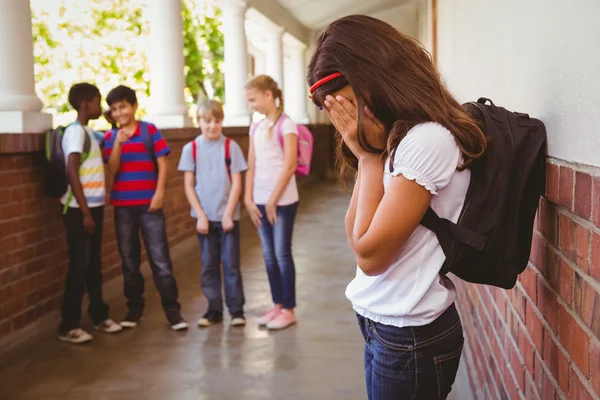 Sorgliga skolflicka med vänner i bakgrunden på skolan korridor — Stockfoto