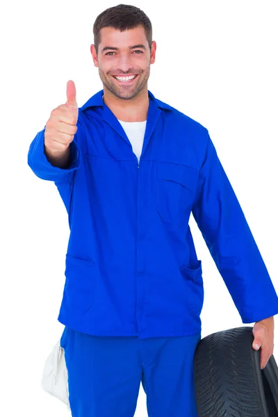 Mechanic with tire gesturing thumbs up — Stock Photo, Image