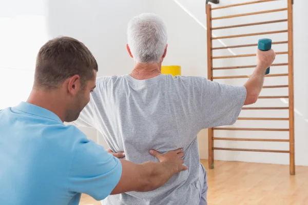 Senior man uit te werken met zijn trainer — Stockfoto