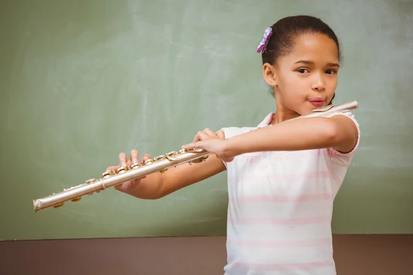 Little girl playing flute in classroom — Stock Photo, Image