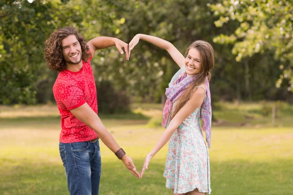 Cute couple in the park making heart shape — Stock Photo, Image