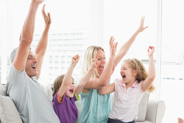 Семья, празднующая успех, смотрит телевизор — стоковое фото