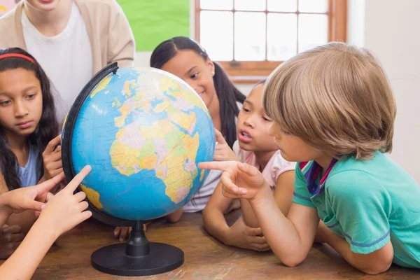 Cute pupils and teacher in classroom with globe — Stock Photo, Image