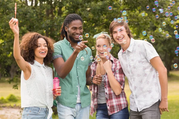 Happy friends in the park blowing bubbles — Stock Photo, Image