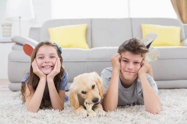 Happy siblings with puppy lying — Stock Photo, Image