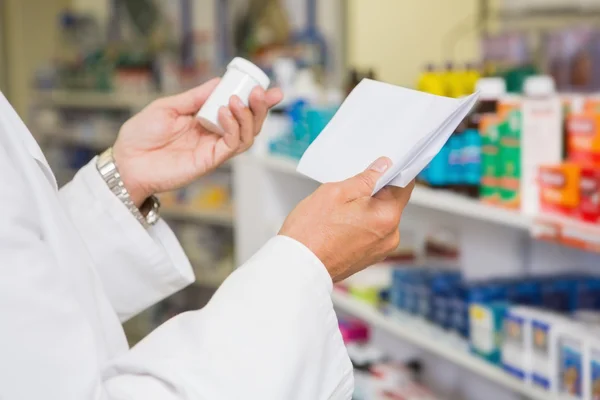 Pharmacist reading prescription and holding medicine — Stock Photo, Image