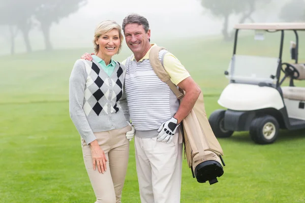 Casal de golfe com buggy de golfe atrás — Fotografia de Stock