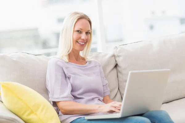 Lachende vrouw op de Bank met behulp van laptop — Stockfoto