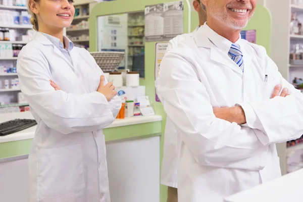 Smiling pharmacist and his trainee with arms crossed — Stock Photo, Image