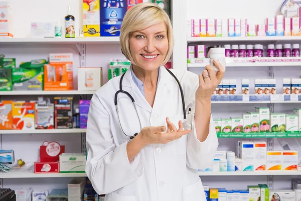 Smiling pharmacist showing medication at camera — Stock Photo, Image