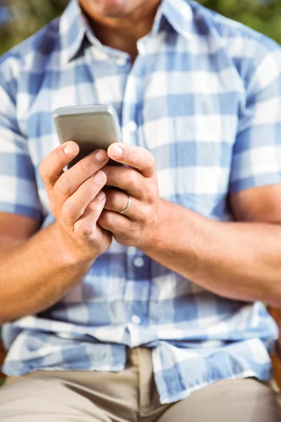 Man zit op bankje met telefoon — Stockfoto