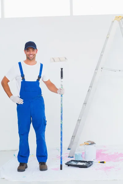 Handyman in overalls holding paint roller — Stock Photo, Image