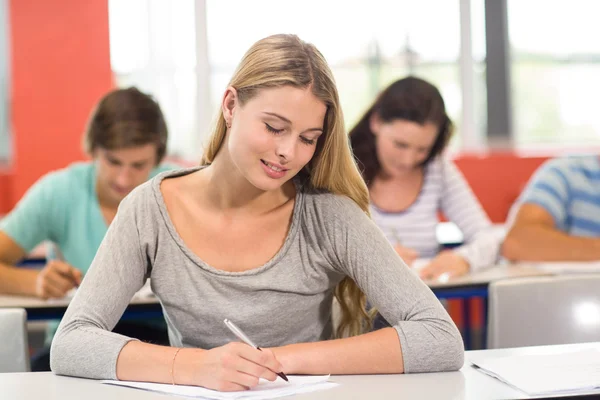 Vrouwelijke student schrijven nota's in de klas — Stockfoto