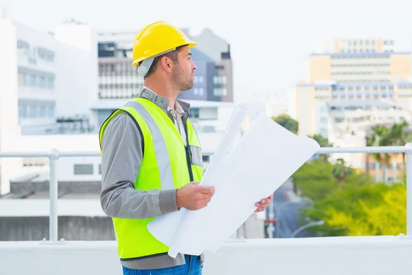 Architect in beschermende werkkleding houden blauwdrukken — Stockfoto