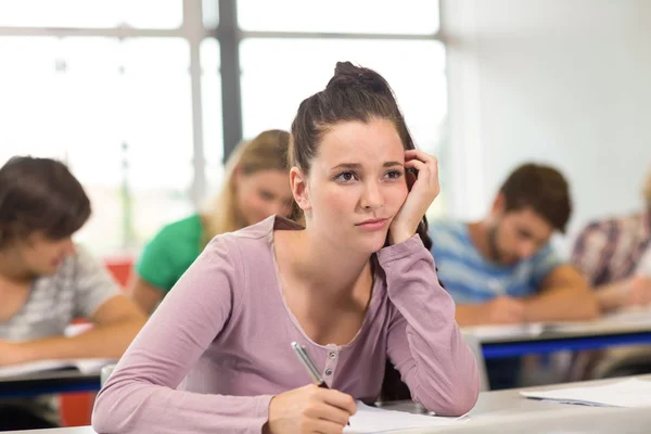 Kvinnlig student skriva noter i klassrummet — Stockfoto