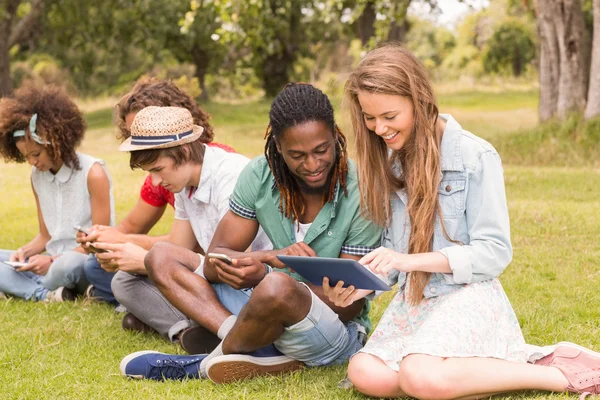 Glückliche Freunde im Park schauen auf Tablet — Stockfoto