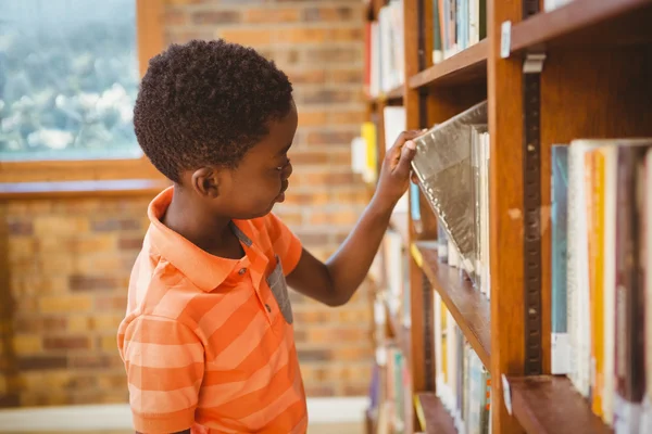 Vista lateral do menino selecionando livro na biblioteca — Fotografia de Stock