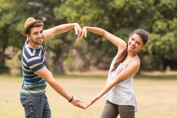 Cute couple in the park making heart shape — Stock Photo, Image