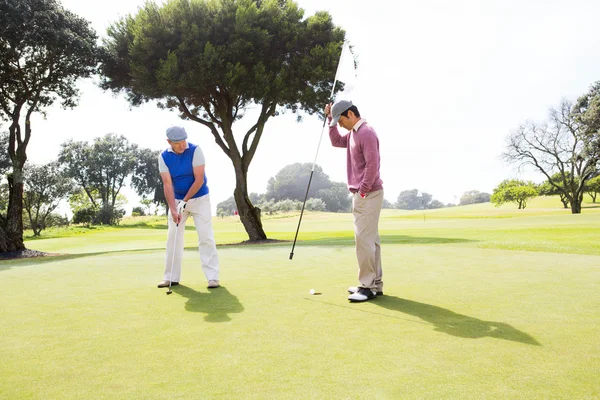 Golfista balançando seu clube com amigo — Fotografia de Stock